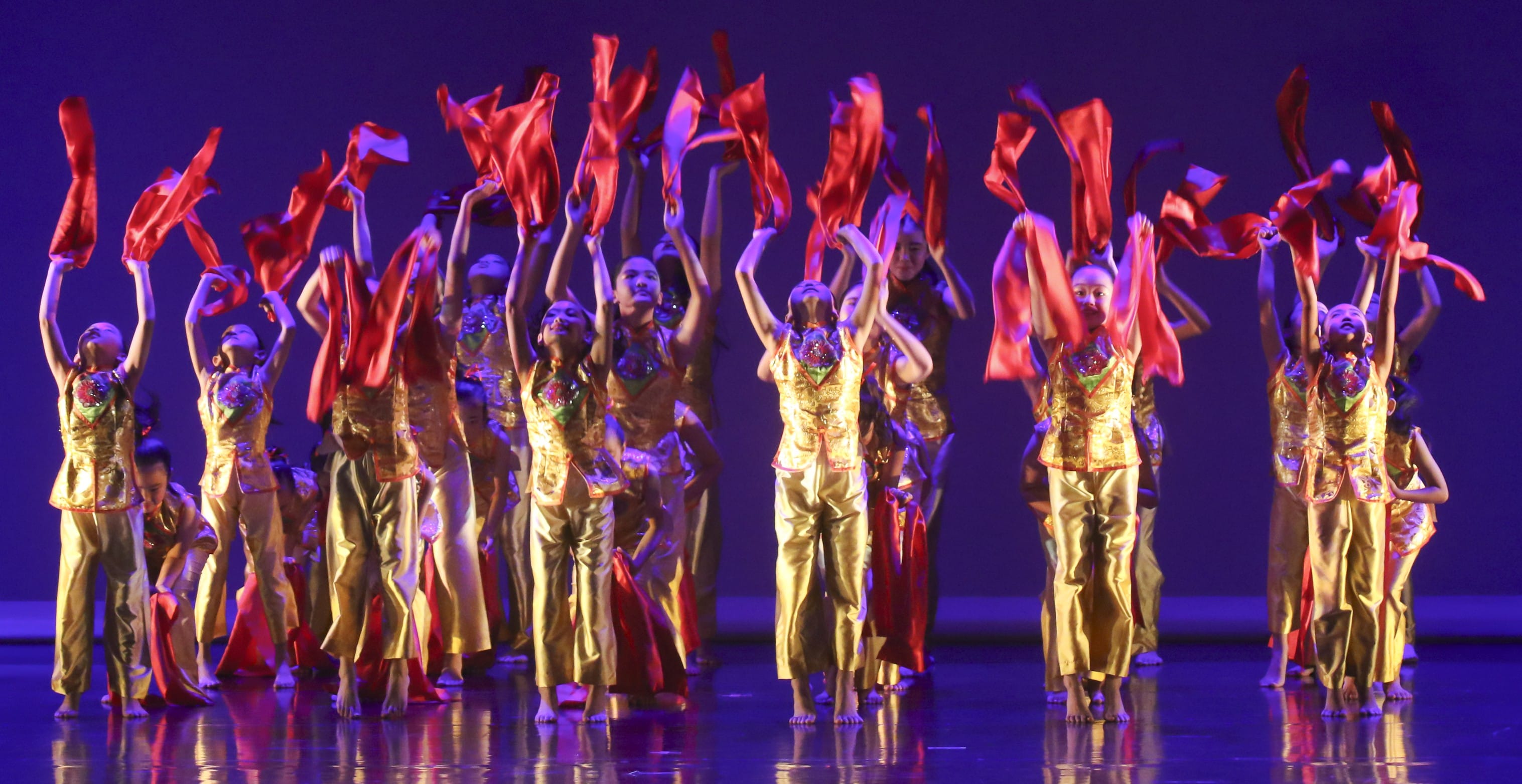 Students performing a dance routine wearing brilliantly bright costumes
